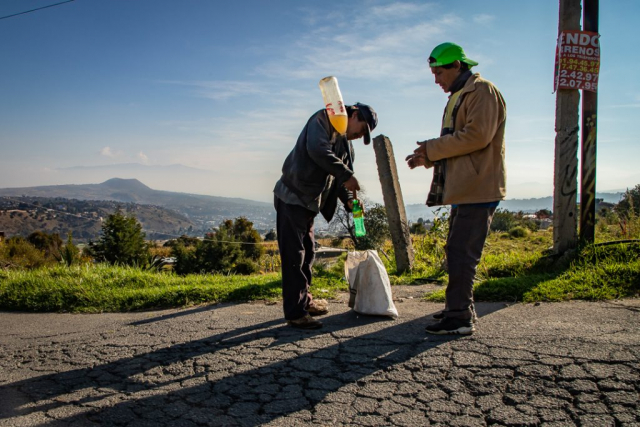 Campesino vendiendo aguamiel a un hombre en la calle con cielo azul de fondo